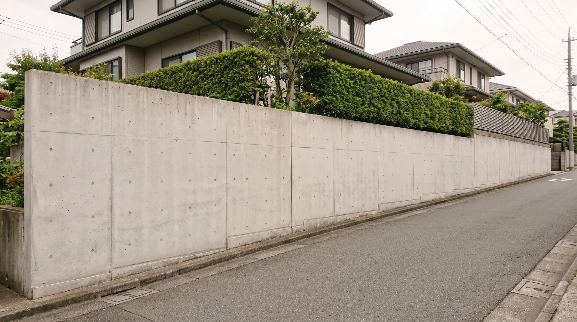 坂の多い住宅地の、コンクリート打放しの擁壁（イメージ）
